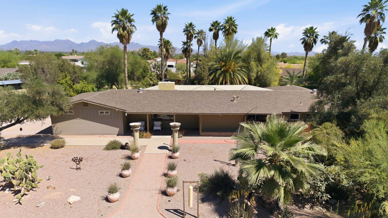 Front view of a single-story ranch home with palm trees and desert landscaping in Paradise Valley, Arizona